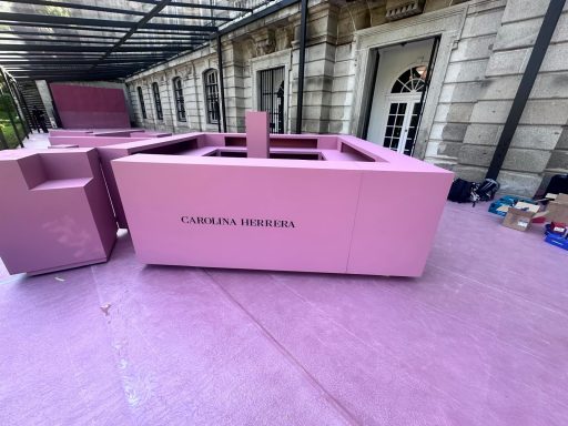 CH CAROLINA HERRERA 2026 Mueble rosa en un espacio exterior con detalles minimalistas y fondo de pared clara.
